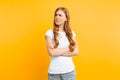 Portrait of an upset young girl standing with folded arms and offended face, on yellow background Royalty Free Stock Photo