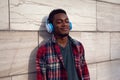 Portrait urban smiling african man in wireless headphones enjoying listening to music on gray wall background Royalty Free Stock Photo