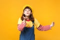 Portrait of ute girl teenager in french beret, denim sundress blowing sending air kiss isolated on yellow wall Royalty Free Stock Photo