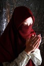 A portrait of a veiled Asian woman praying in an Islamic way. beautiful Muslim model wearing red clothes