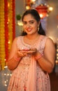 portrait vertical shot of Happy Indian young woman looking at camera by holding diwali diya lamp at home - concept of Royalty Free Stock Photo