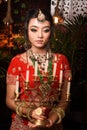 Portrait of very beautiful young attractive Indian lady in luxurious costume with makeup and heavy jewellery holding candelabra in Royalty Free Stock Photo