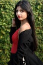 Portrait of very beautiful young attractive woman wearing red outfit with black jacket posing fashionable in a blurred green Royalty Free Stock Photo