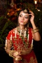 Portrait of very beautiful young Indian bride in luxurious bridal costume with makeup and heavy jewellery holding candelabra in Royalty Free Stock Photo