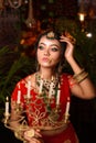 Portrait of very beautiful young Indian bride in luxurious bridal costume with makeup and heavy jewellery holding candelabra in Royalty Free Stock Photo