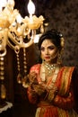 Portrait of very beautiful young Indian bride in luxurious bridal costume with makeup and heavy jewellery looking at Chandelier. Royalty Free Stock Photo