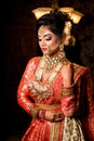 Portrait of very beautiful young Indian bride in luxurious bridal costume with makeup and heavy jewellery in studio lighting Royalty Free Stock Photo