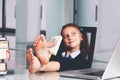 Portrait of very happy cute young business girl with bare feet on the table and counts money profit. Selective focus on bare feet