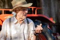 Portrait of very old farmer with straw hat explaining life in front of a red tractor Royalty Free Stock Photo
