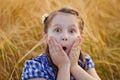 Portrait of a very surprised cute little girl in a field of wheat in the open air. Nature in the village Royalty Free Stock Photo