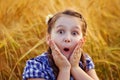 Portrait of a very surprised cute little girl in a field of wheat in the open air. Nature in the village Royalty Free Stock Photo