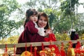 Portrait of Vietnamese woman and her daughter in red dress with traditional Vietnamese New Year decorations on the street of city. Royalty Free Stock Photo