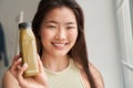 Girl smiling toothy and looking straight while showing bottle with smoothie Royalty Free Stock Photo