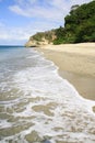 Portrait view of beach, crystal clear waters, blue sky and a rock formation