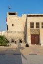 Portrait view of entrance of the Ras al Khaimah Museum in the morning sun with flags blowing