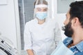 Female dentist in protective mask talking with her male patient Royalty Free Stock Photo