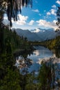 A portrait view framed by foliage of the incredibly beautiful Lake Matheson, New Zealand with the reflection of the stunning South Royalty Free Stock Photo