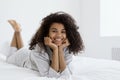 Cheerful young afro american woman lying on bed, looking at camera Royalty Free Stock Photo