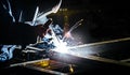 Portrait view of professional mask protected welder. Bright electric torch burns iron piece Royalty Free Stock Photo