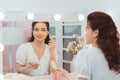 Portrait view of young adult asian woman looking at mirror, sitting in bright room and making make up. Beautiful and professional Royalty Free Stock Photo