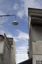 Portrait of vintage lamp hanging on a pole in the city, blue sky and cloud in background.