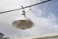 Portrait of vintage lamp hanging on a wire in the city, blue sky and cloud in background,selective focus.