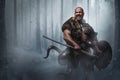 Aggressive Viking warrior with shield and axe in winter forest