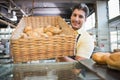 Portrait of waiter in apron showing basket of bread