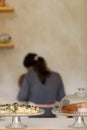 Portrait of waitress in apron from back, standing at shop counter and doing work, homemade cake and pie on a cafe corner