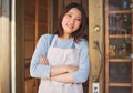 Portrait, waitress and Asian woman with arms crossed at door of restaurant, coffee shop or store. Face, smile and Royalty Free Stock Photo