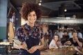 Portrait Of Waitress Holding Menus Serving In Busy Bar Restaurant