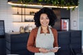 Portrait waitress of a small business owner of a cafe, woman in apron smiles and looks at camera with a tablet computer