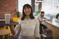 Portrait of waitress with smoothie glass while businessman using laptop