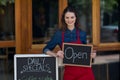 Portrait of waitress standing with chalkboard and menu