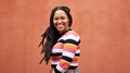 Portrait, wall and black woman with smile, fashion and freedom with joy, success and casual outfit. Face, Jamaican