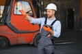 Portrait of warehouse forklift driver standing in storehouse by the machine. Royalty Free Stock Photo