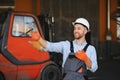 Portrait of warehouse forklift driver standing in storehouse by the machine. Royalty Free Stock Photo