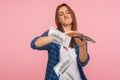 Portrait of wasteful rich girl in checkered shirt scattering dollars with arrogant grimace, boasting wealthy life Royalty Free Stock Photo