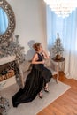 Portrait of a wealthy mature woman with evening make-up and hairstyle posing in a black dress on the background of the Royalty Free Stock Photo