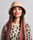 Portrait of wealthy woman with colored straight hair in leopard pattern print pullover sweater and hat looking at camera