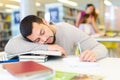 Portrait of upset adult man with stack of books on table in room of public library