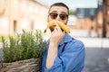 Portrait of weird stylish businessman with banana outdoors