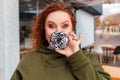 Portrait of a well-fed surprised woman covering her face with a chocolate donut. The concept of diet and obesity