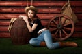 Portrait of western girl in jeans and cowboy hat near wagon wheel and big barrel Cowgirl, rodeo girl. Royalty Free Stock Photo