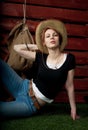 Portrait of western girl in jeans and cowboy hat near wooden wagon wheel. Cowgirl, rodeo girl. Royalty Free Stock Photo