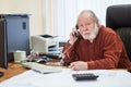 Portrait of white bearded senior businessman using telephone, calling to somebody while working in office