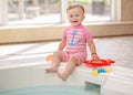 Portrait of white Caucasian baby girl laughing sitting on swimming-pool nosing
