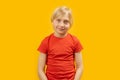 Portrait of white-haired caucasian boy of 8-10 years old in red T-shirt on yellow background. Straight look