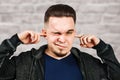 Portrait White man closes the ears in blue shirt on brick wall background