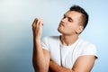 Portrait of a white man on a light background, looking at his nails. The concept of body language, expression of emotions,